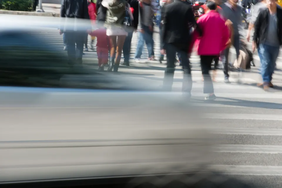People in crosswalk with blurred fast car passing in foreground